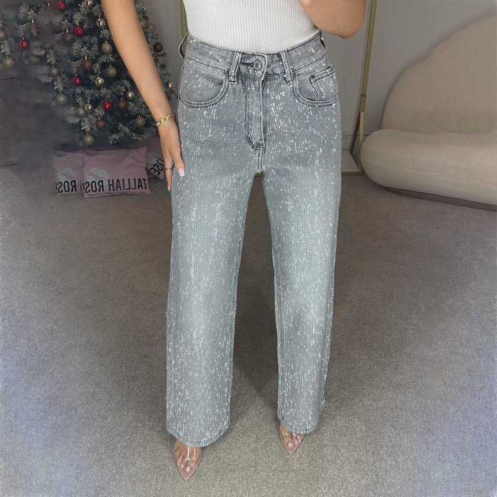 Woman wearing high-waisted silver sequin wide-leg jeans with clear strap heels in modern room