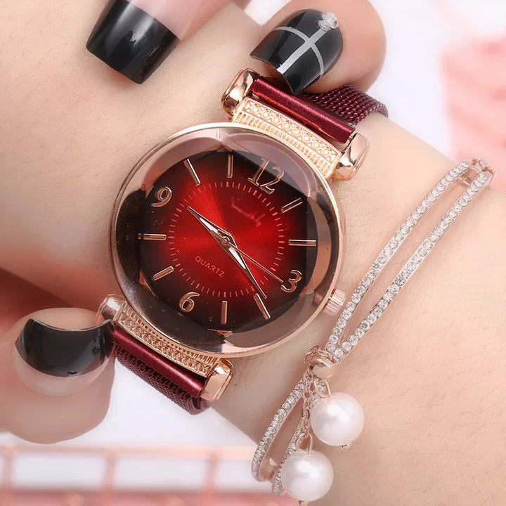 Close-up of wrist wearing red and gold quartz watch with mesh band and rhinestone bracelet with pearls