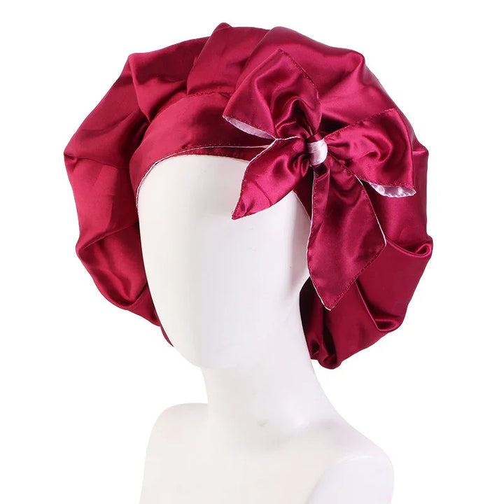 Red satin bonnet with large bow detail on a white mannequin head