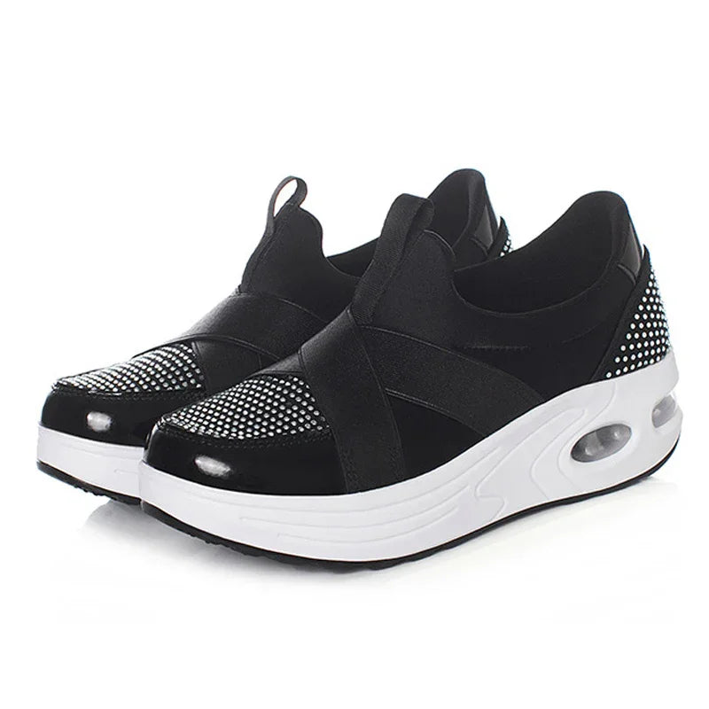 Black slip-on sneakers with white soles and rhinestone embellishments on toe and heel