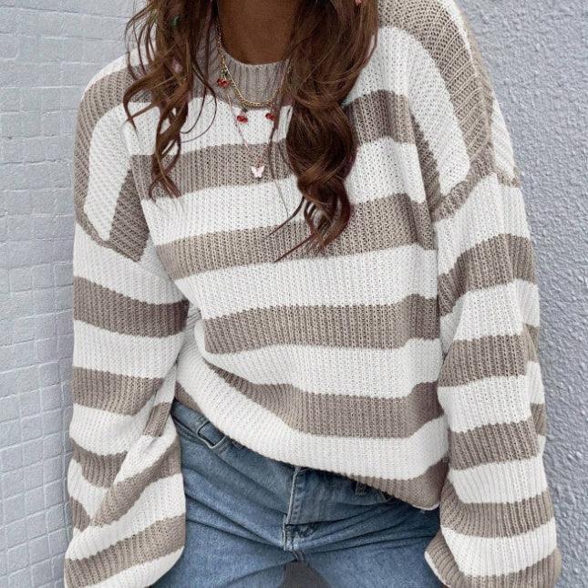 Person wearing oversized beige and white striped knit sweater and blue jeans with layered necklaces