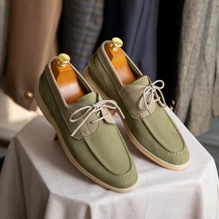 Pair of olive green casual men's lace-up shoes on a white cloth-covered table with wooden shoe trees