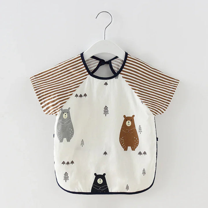 Baby bib with striped brown sleeves and cute bear and tree prints on white fabric, hanging on white hanger