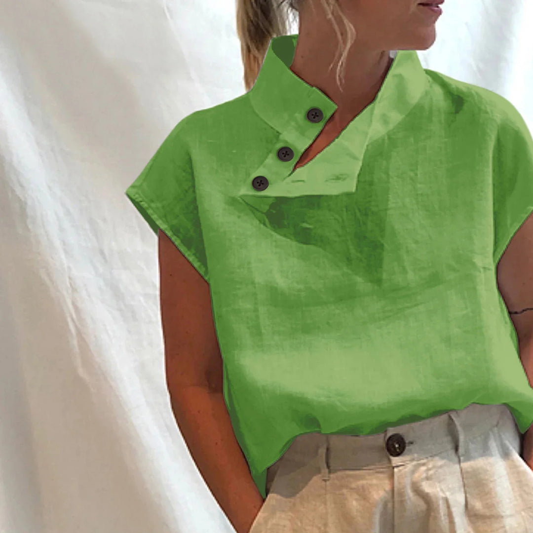 Woman wearing a bright green short-sleeve top with an asymmetric buttoned collar and beige pants