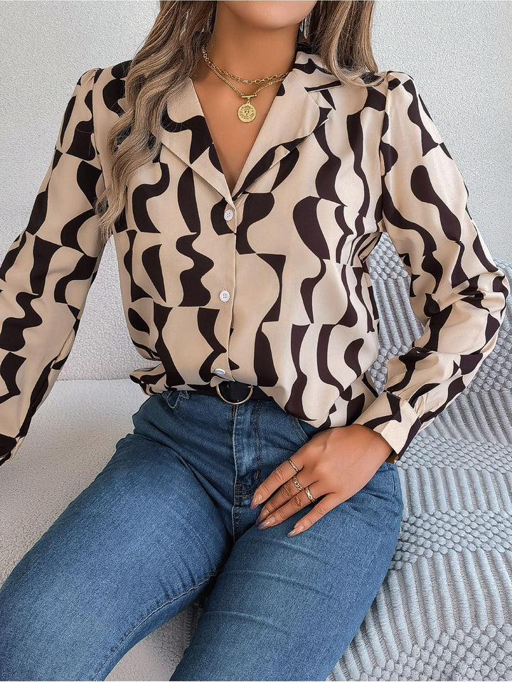 Woman wearing a black and beige abstract print button-up shirt paired with blue jeans and gold jewelry