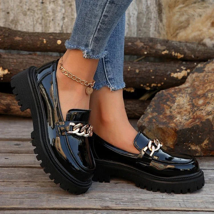 Black patent leather chunky loafers with gold chain detail worn with blue frayed hem skinny jeans and gold anklet