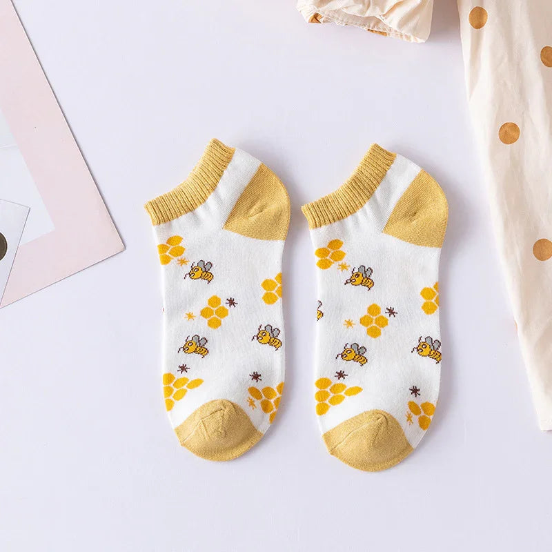 Pair of white ankle socks with yellow bees and honeycomb pattern, yellow heels and cuffs