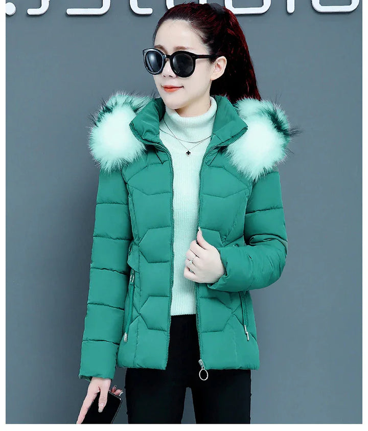 Woman wearing green padded winter jacket with faux fur hood and black sunglasses