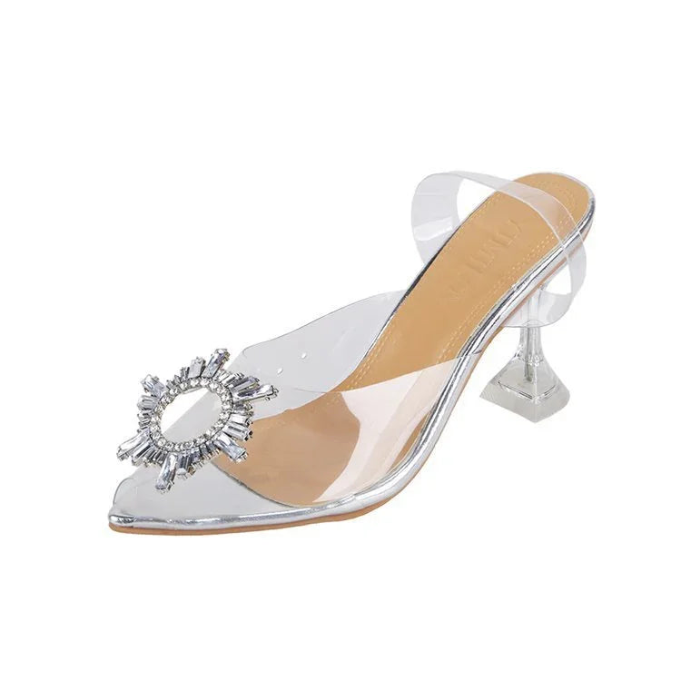 Clear mule heel shoe with pointed toe, jeweled embellishment, and transparent strap
