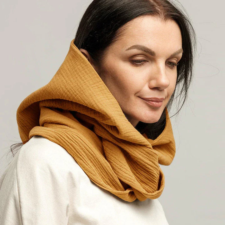 Woman wearing mustard yellow textured cotton hooded scarf and white top on neutral background