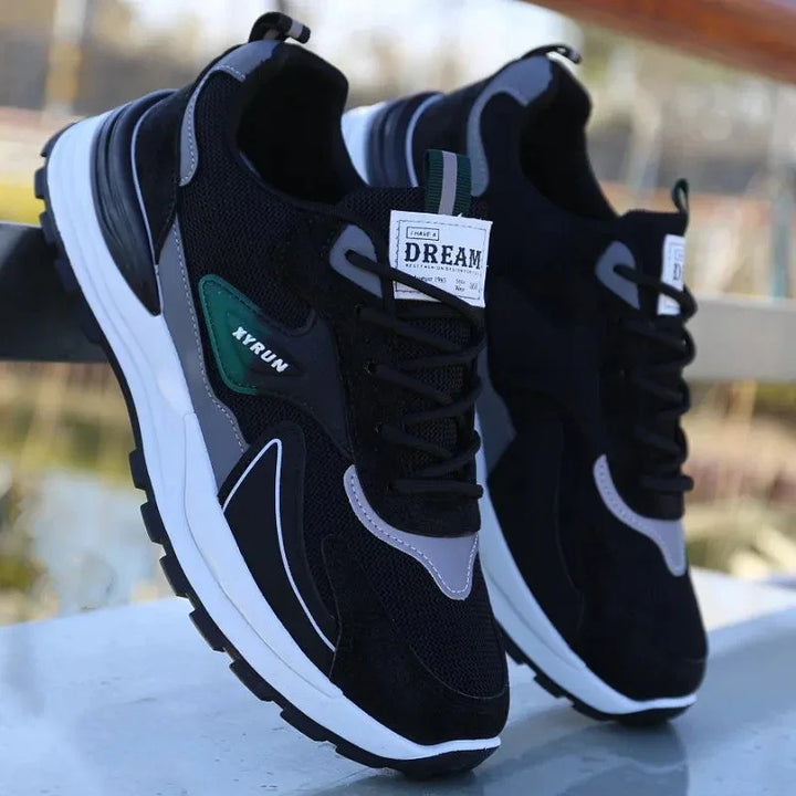 Black and gray XYRUN athletic sneakers with white soles and 'I Have A Dream' label on the tongue, outdoor setting