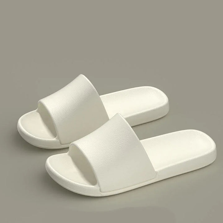 Pair of white slip-on foam sandals on a gray background, minimalist and comfortable slides