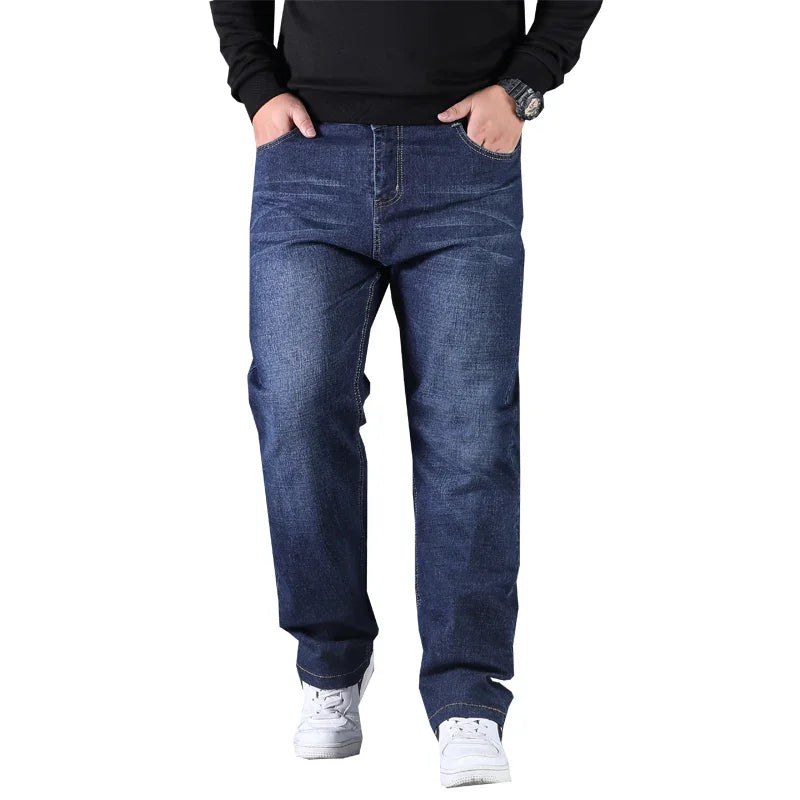 Man wearing dark blue straight fit jeans with hands in pockets and white sneakers