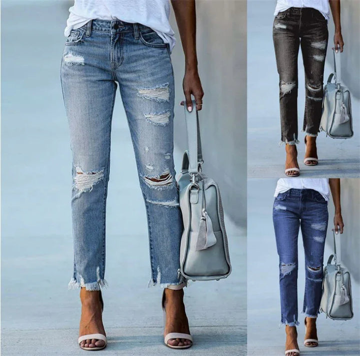 Women's distressed ripped jeans in light blue, black, and dark blue with frayed hems, styled with white top and heels