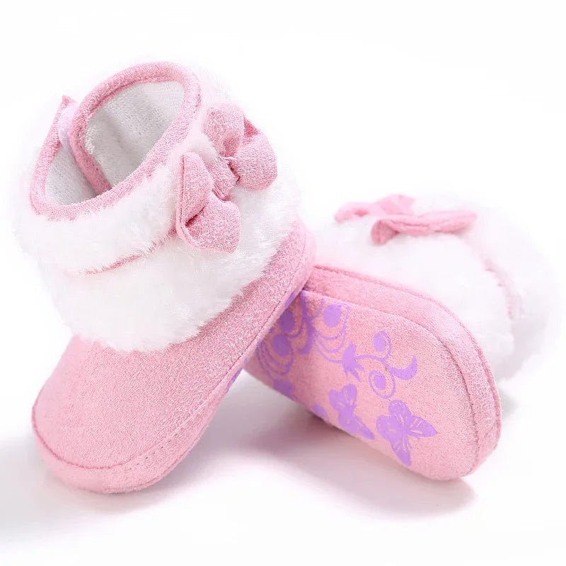 Soft pink baby booties with white fuzzy trim and small bow detail, floral grip sole