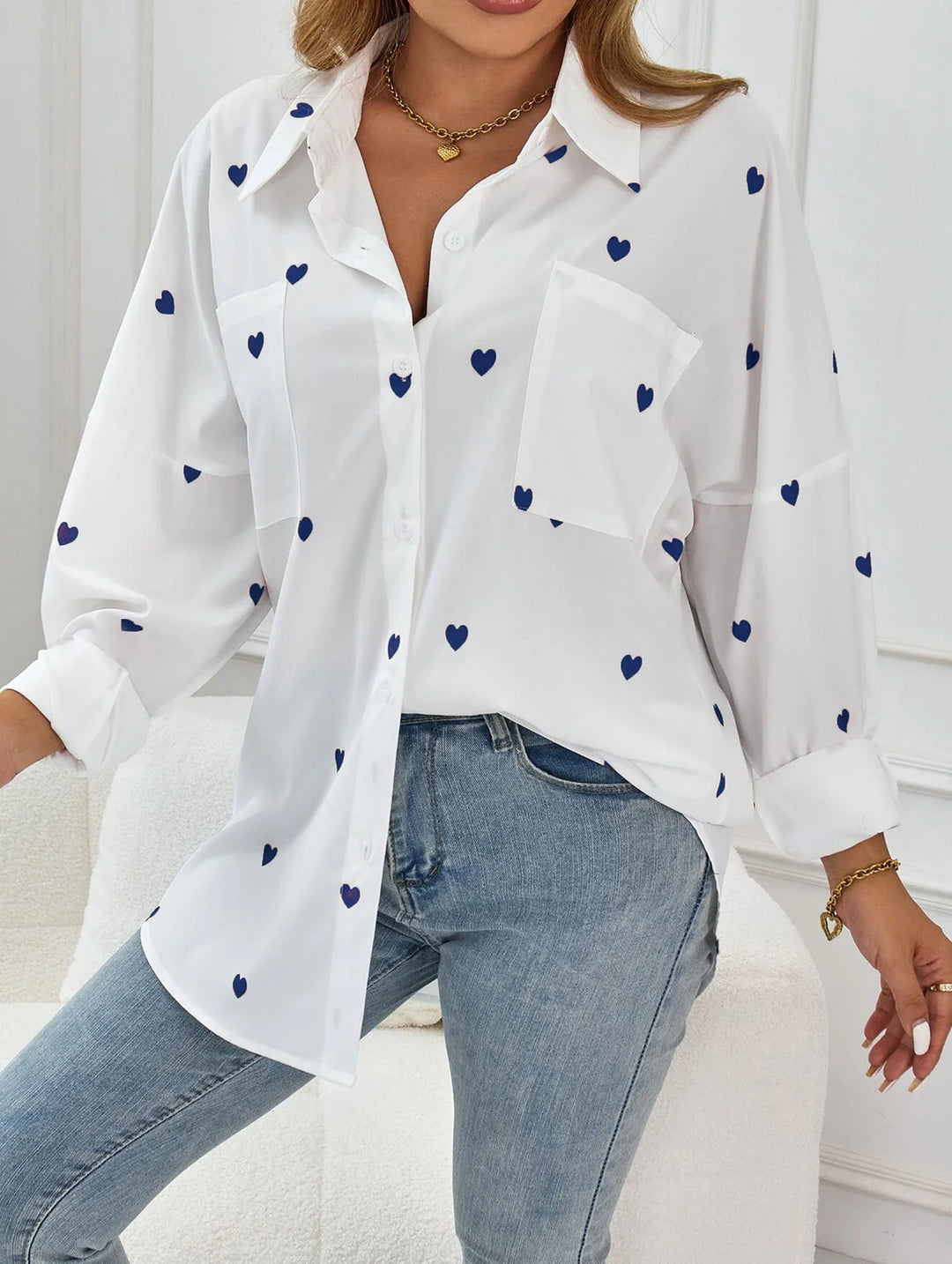 Woman wearing white button-up blouse with blue heart prints and light wash jeans