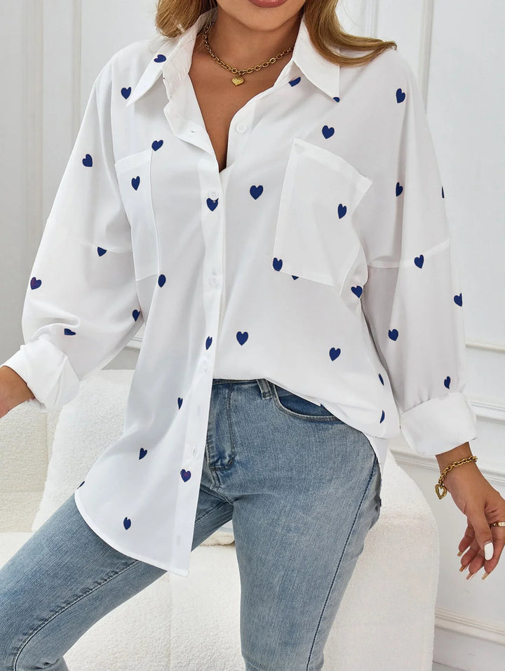 Woman wearing white button-up blouse with blue heart prints and light wash jeans