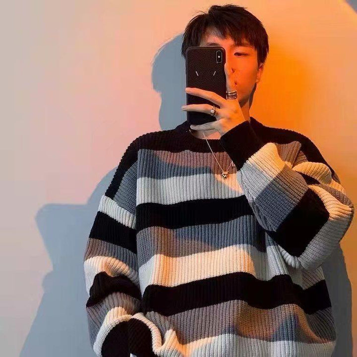 Young man taking selfie wearing a black, white, and gray striped knit sweater in warm lighting
