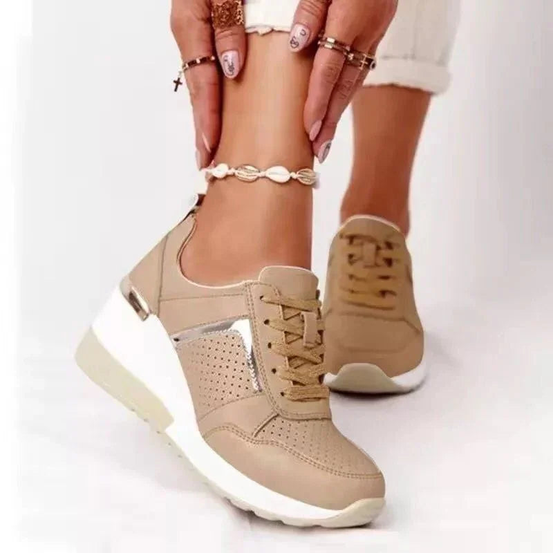 Beige platform sneakers with perforated detailing and metallic accents worn with shell anklet and rings