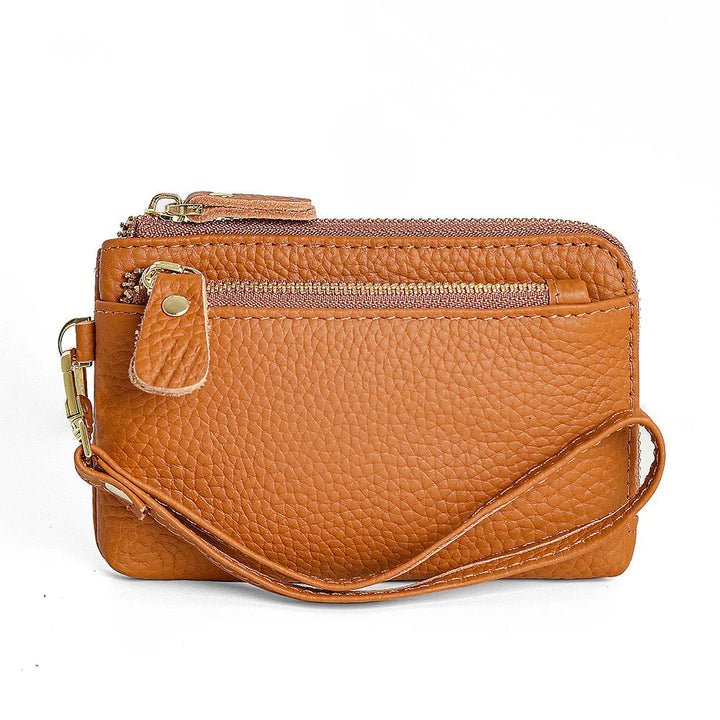 Brown textured leather wristlet wallet with front zipper pocket and strap on white background