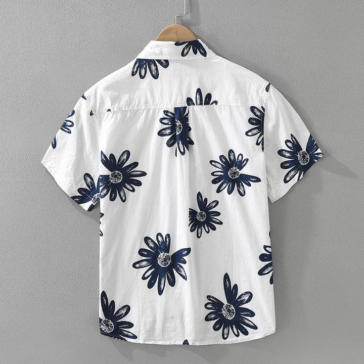 White short-sleeve shirt with large navy blue floral print hanging on wooden hanger