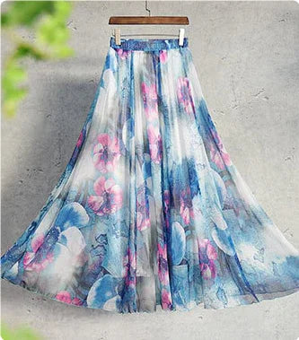 Flowy maxi skirt with blue and pink floral print hanging on wooden hanger against gray wall
