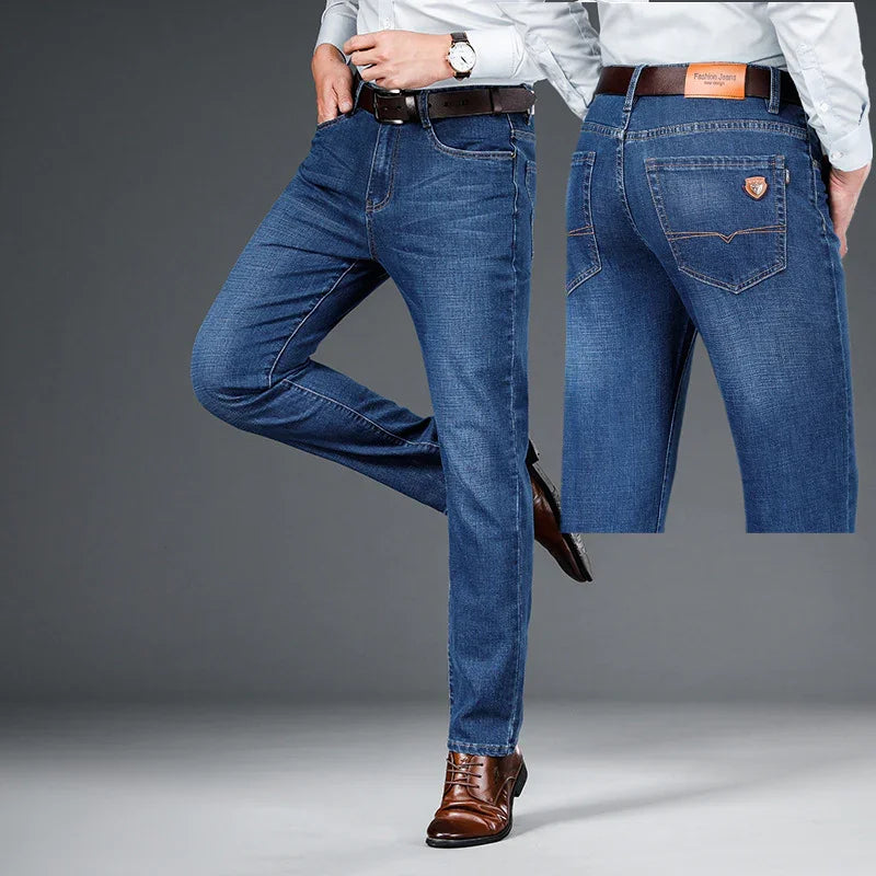 Men's slim-fit blue denim jeans styled with brown leather belt and matching brown dress shoes