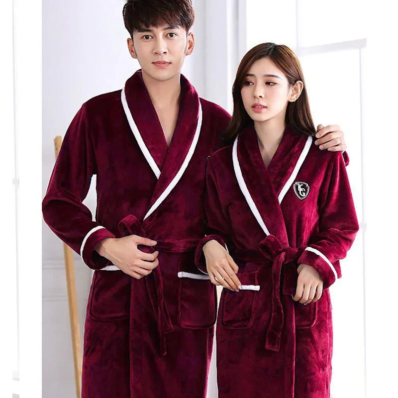 Man and woman wearing matching burgundy plush bathrobes with white trim in bright indoor setting