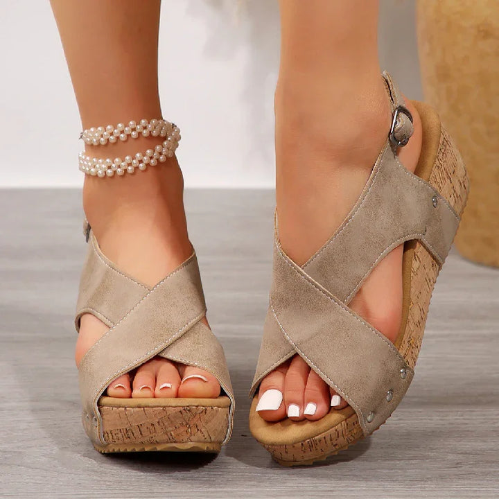Beige suede wedge sandals with crisscross straps on feet with french pedicure and pearl anklet