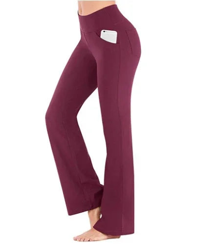Woman wearing maroon yoga pants with phone in side pocket, barefoot studio pose