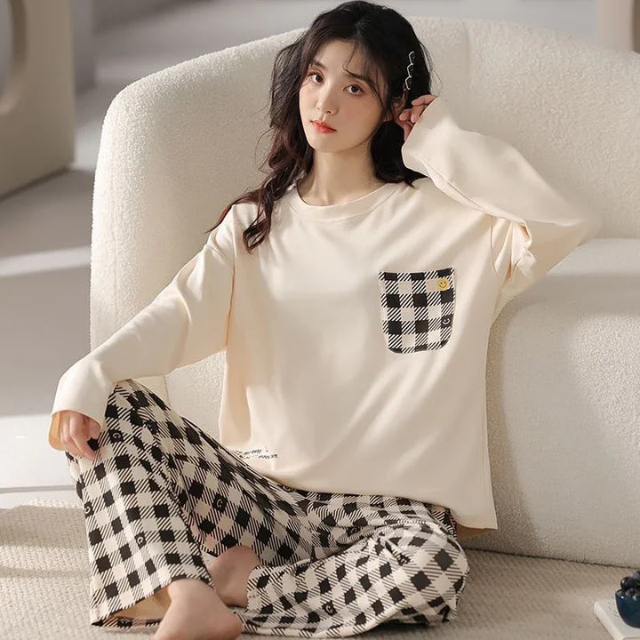 woman wearing cream long sleeve top with checkered pocket and matching checkered pants sitting on white sofa