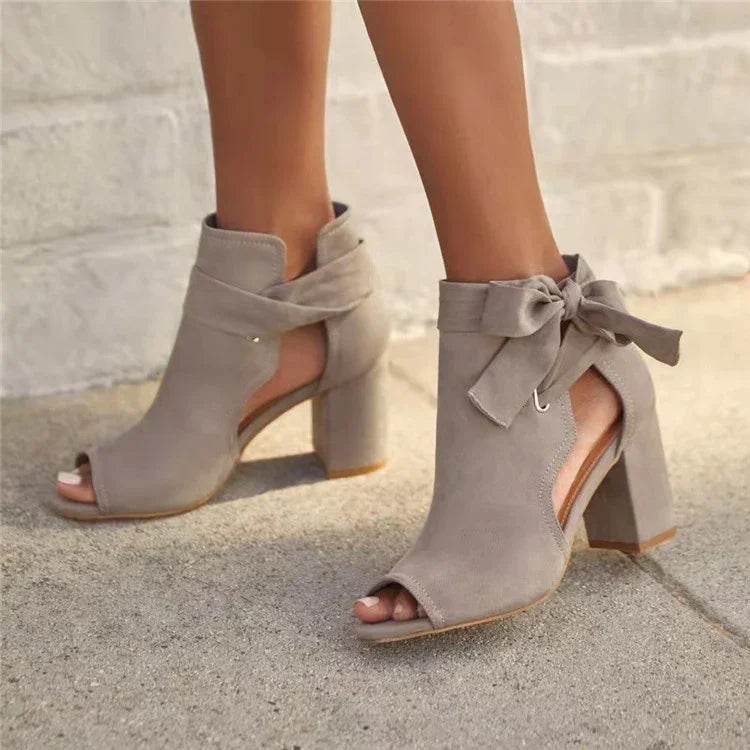 women's taupe suede open-toe block heel ankle boots with bow detail on sidewalk