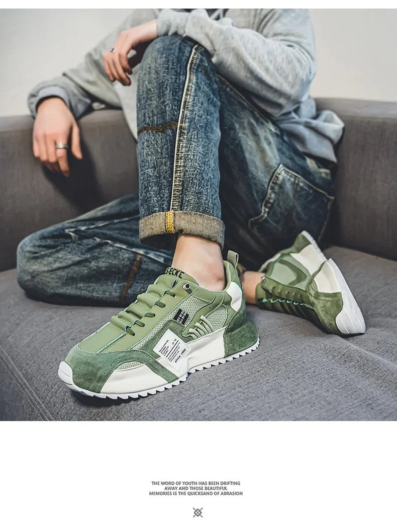 Casual green and white sneakers worn with rolled-up blue jeans on a grey sofa