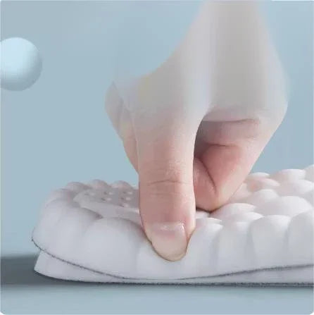Hand pressing soft, white cushioned insole against blue background, showcasing comfort
