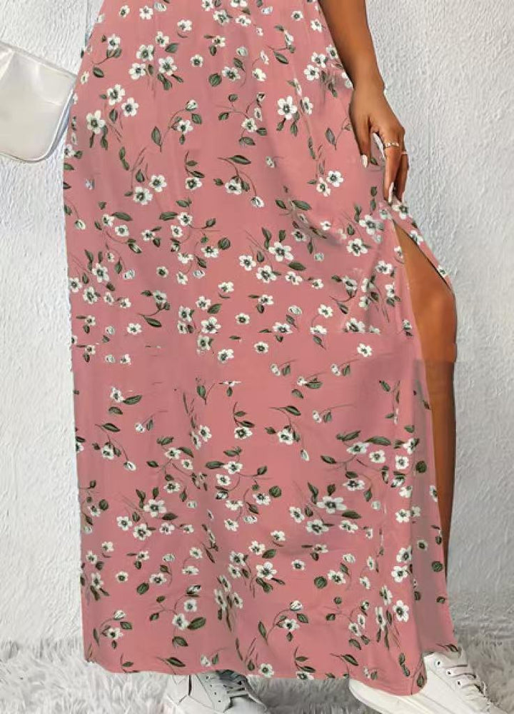 Woman wearing a pink floral maxi dress with side slit and white sneakers against white wall