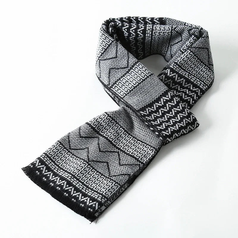 Black and gray patterned woven scarf with geometric designs and fringed ends on white background
