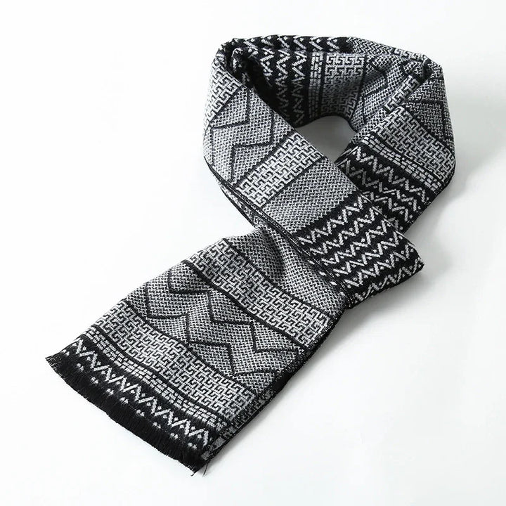 Black and gray patterned woven scarf with geometric designs and fringed ends on white background