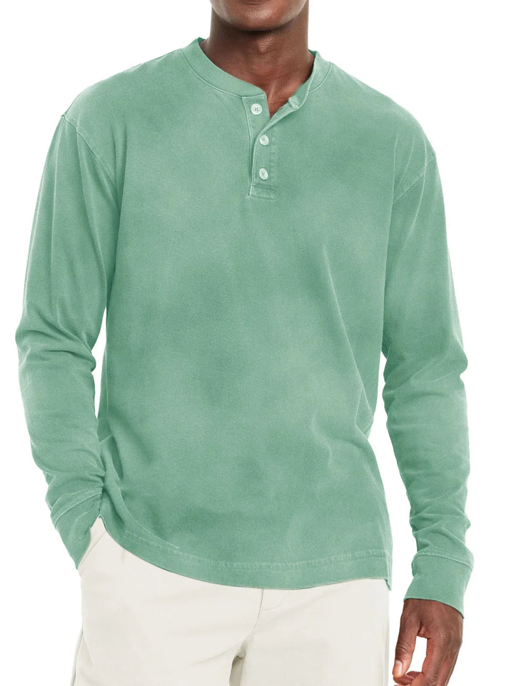 Man wearing soft green long sleeve henley shirt with three buttons, paired with beige pants