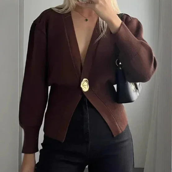 woman wearing deep brown cardigan with gold button, black high-waist pants, holding black shoulder bag