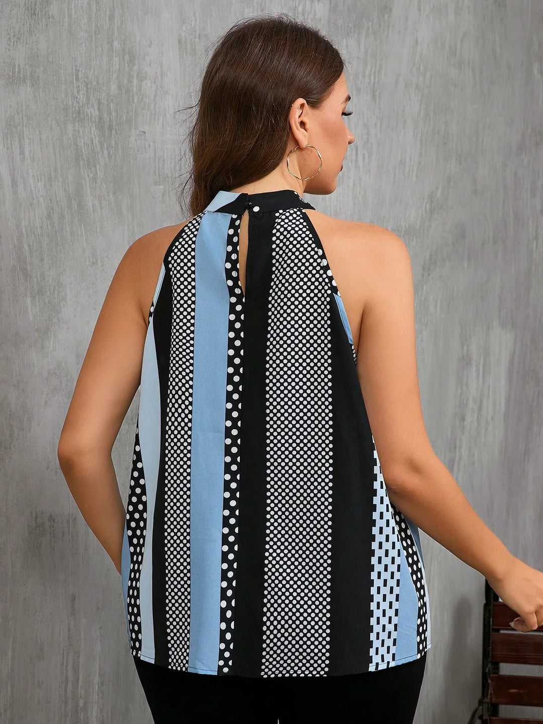Woman wearing sleeveless halter neck top with blue, black, white vertical stripes and polka dot pattern