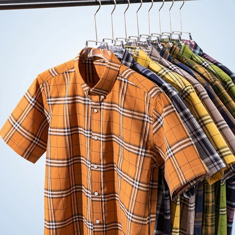 Short-sleeve plaid button-up shirts in various colors hanging on a clothing rack
