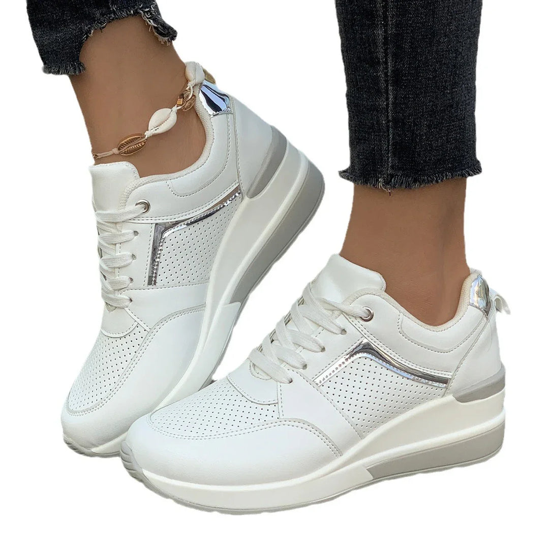 White perforated sneakers with silver accents worn with black frayed hem jeans and shell anklet