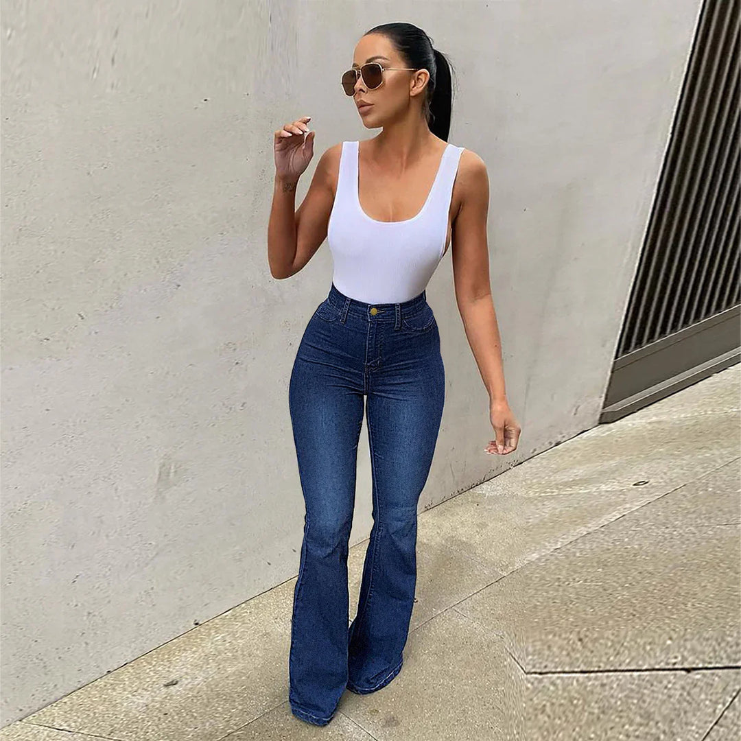 woman wearing white tank top and high-waisted flared blue jeans with sunglasses walking outdoors