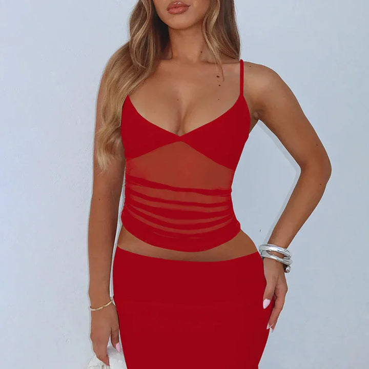 Woman wearing red mesh sheer top with spaghetti straps and matching skirt against white background