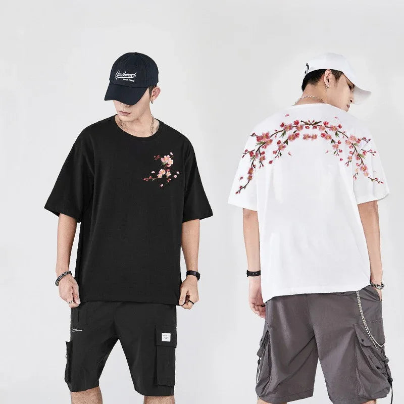 Men wearing black and white casual t-shirts with pink floral designs and cargo shorts, styled with caps