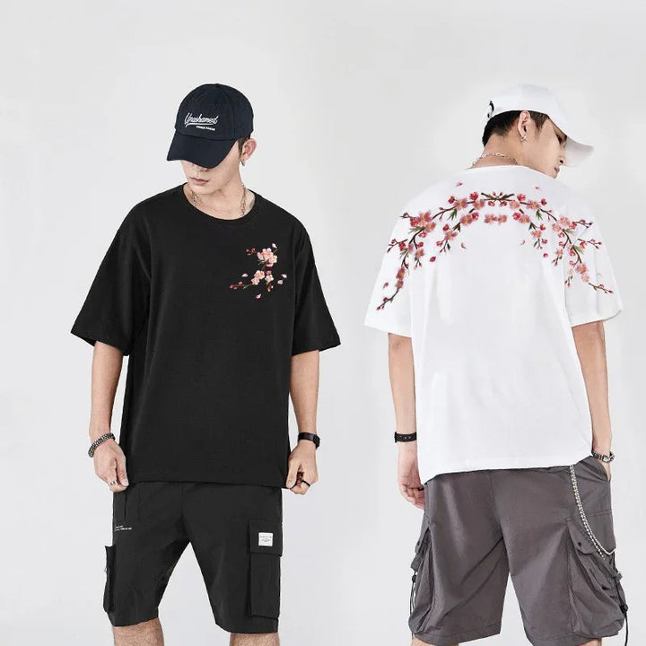 Men wearing black and white casual t-shirts with pink floral designs and cargo shorts, styled with caps