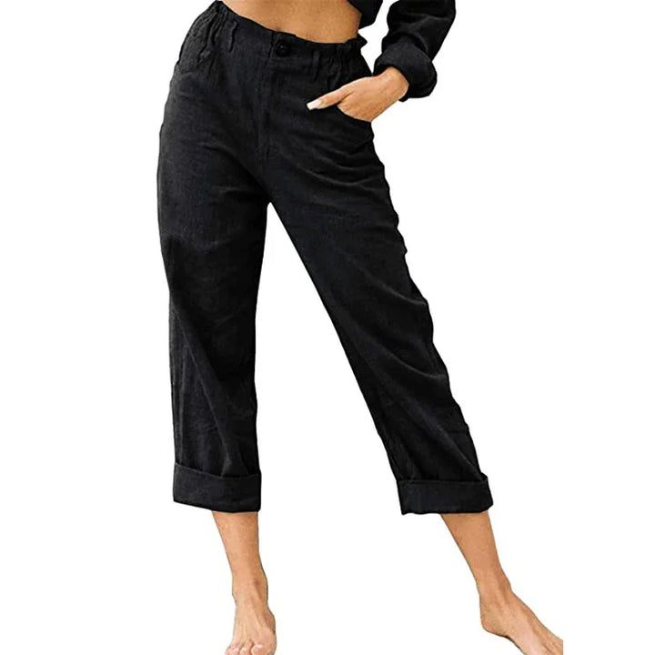 Woman wearing black high-waist tapered pants with elastic waistband and rolled cuffs