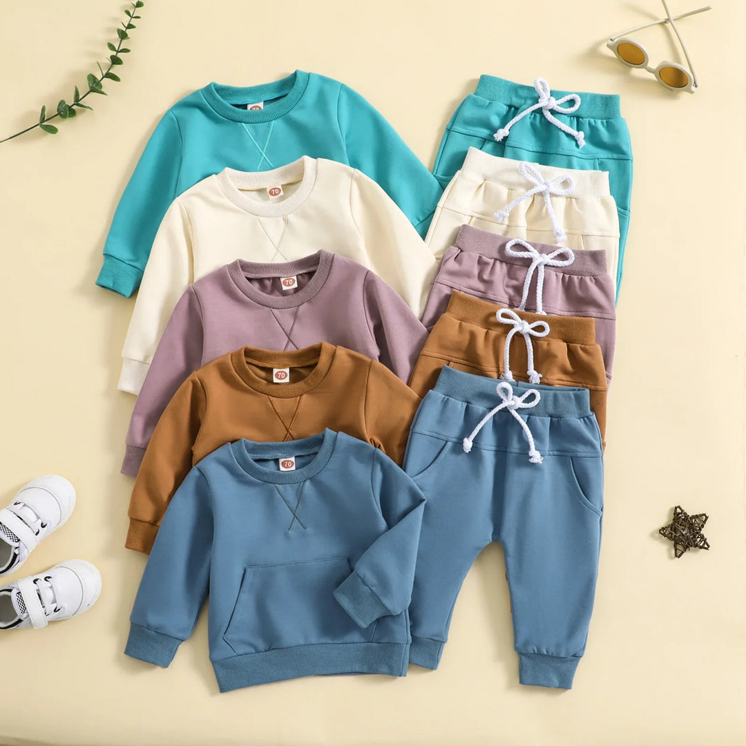 Five sets of colorful toddler sweatshirts and pants in blue, brown, purple, cream, and teal with white drawstrings