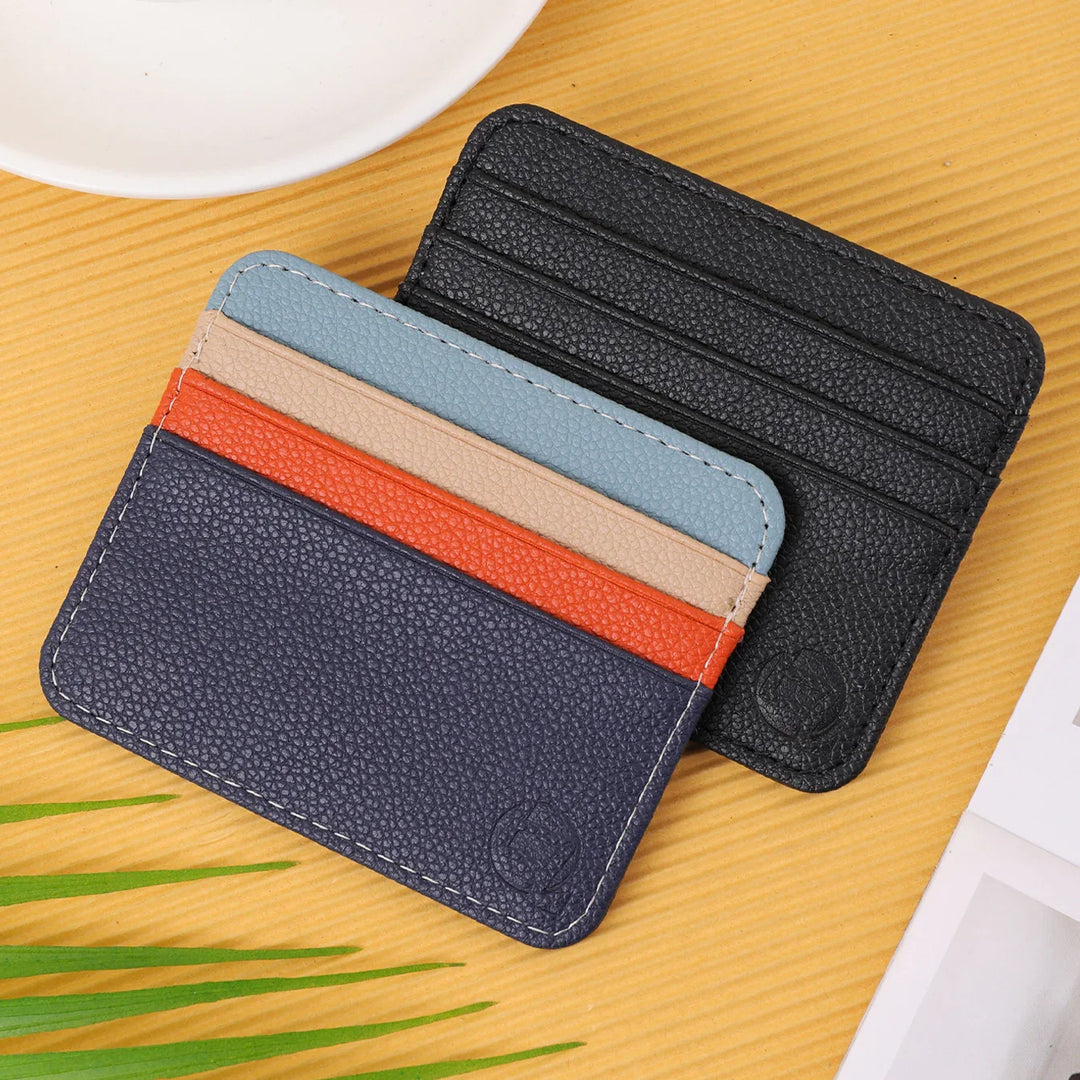 Two leather cardholders on wooden surface, one multicolor with blue, beige, orange, navy stripes, and one black