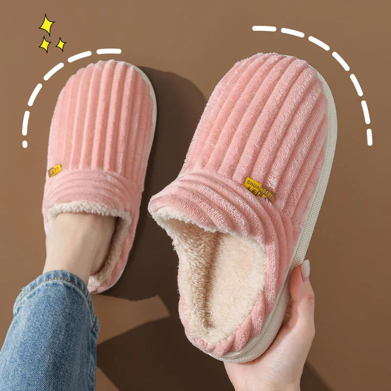 Cozy pink plush slippers with ribbed texture and fleece lining on brown background